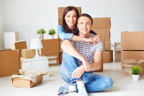 Illustrative couple sitting together amongst moving boxes